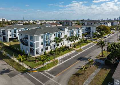 A street view of a residential area with apartment buildings and palm trees.