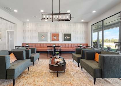 A living room with grey couches and a brown rug.