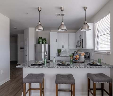 an open kitchen with a marble counter top and stools
