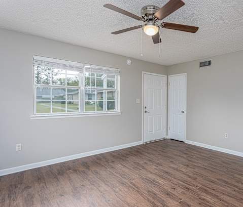 an empty living room with a ceiling fan and a window