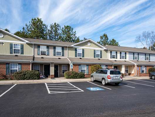 an apartment building with a parking lot and cars in front of it at Pendleton Townhomes Apartments, Durham, NC