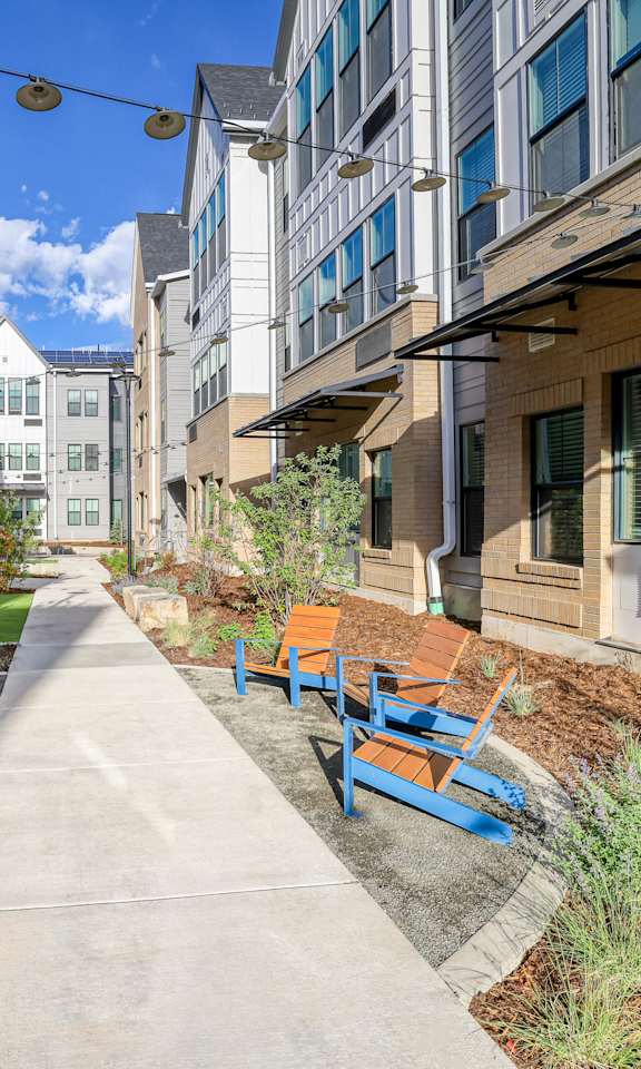 A row of blue benches are lined up on a concrete walkway.
