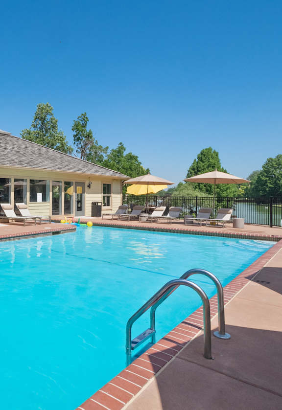 a swimming pool with lounge chairs and umbrellas in front of a building