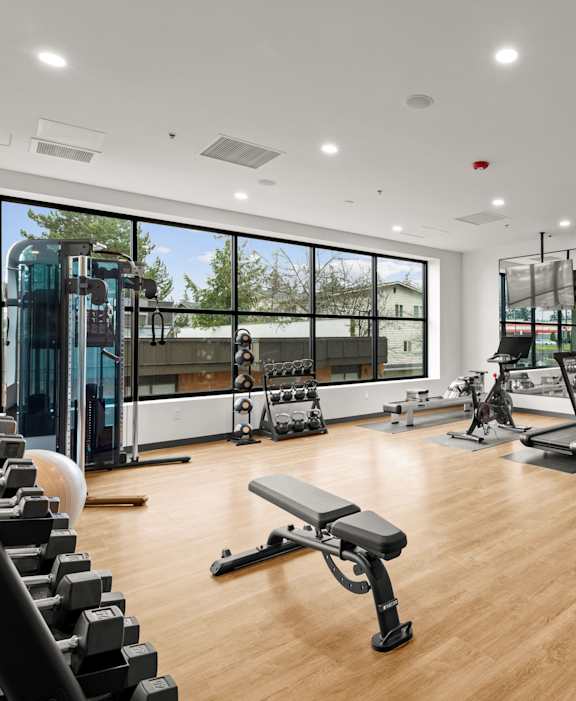 A gym with a variety of equipment including treadmills, weights, and exercise machines at Two 10 by Vintage, Shoreline, WA