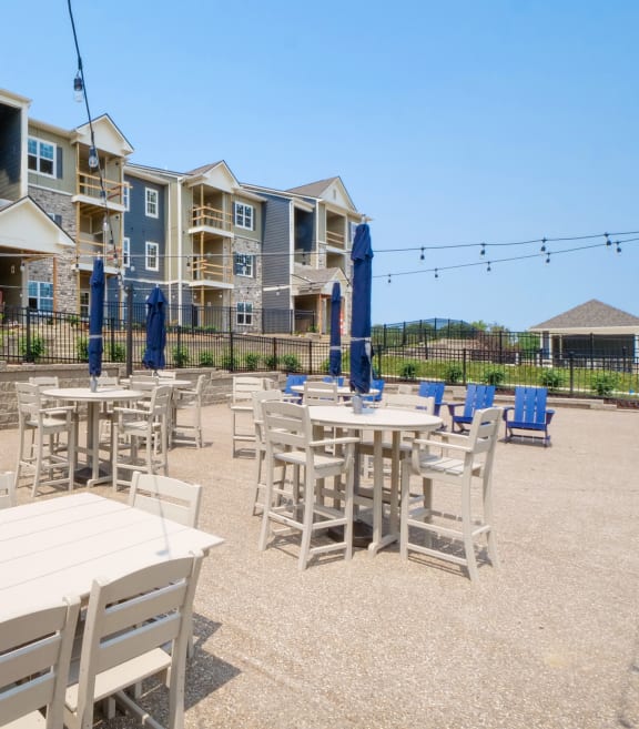 a patio with tables and chairs at the whispering winds apartments in pearland, tx