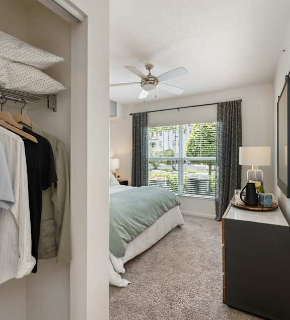 A bedroom with a bed, a dresser, and a window with curtains.