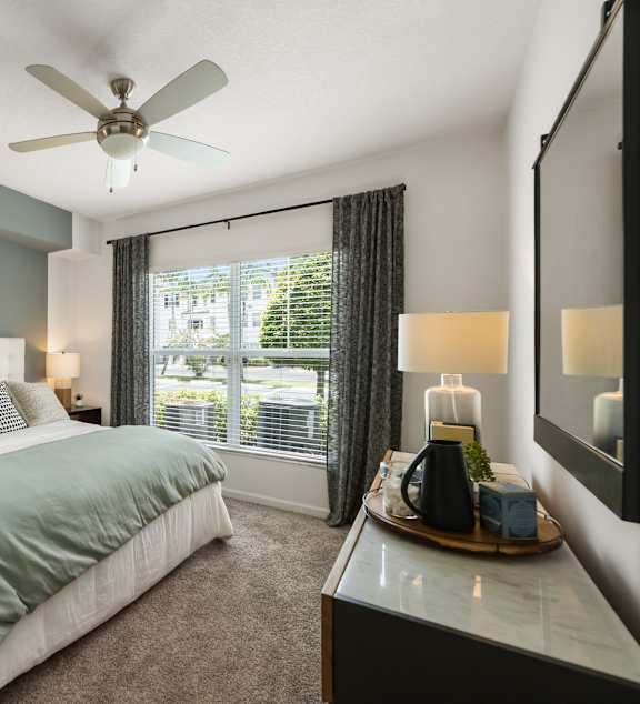 A bedroom with a large bed and a ceiling fan.