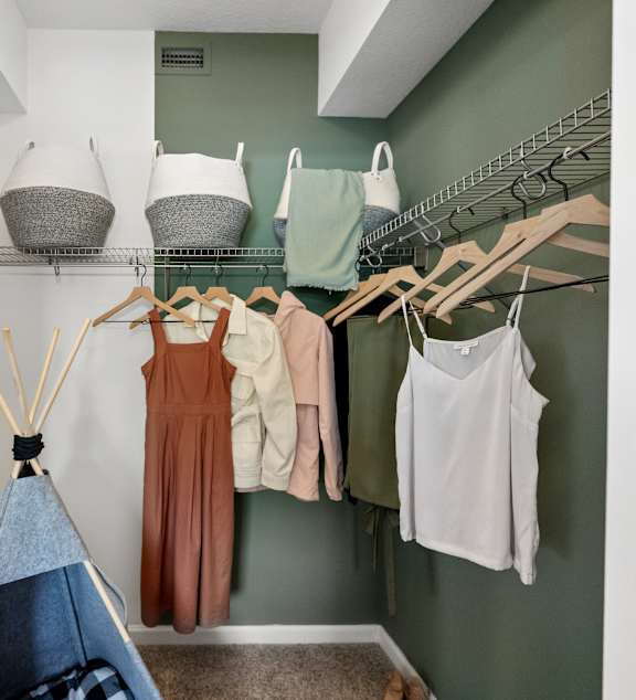 A room with a teepee and clothes hanging on a rack.