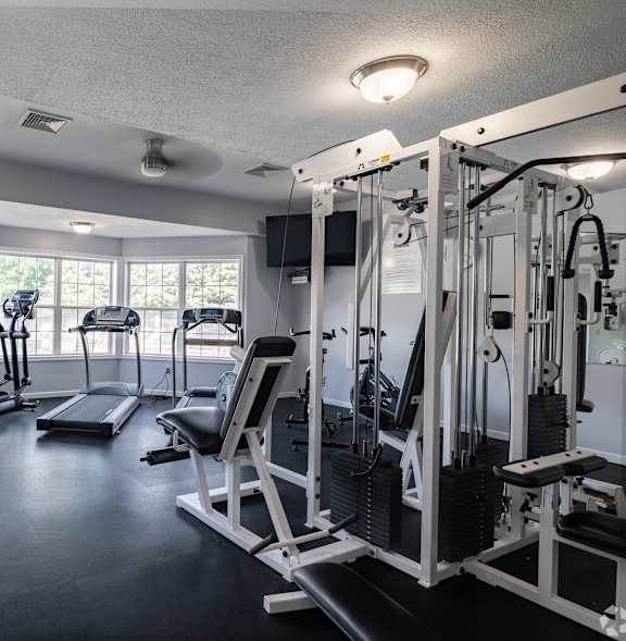 A gym with a variety of equipment including a treadmill, stationary bike, and weight bench.at Highlands of Heritage Woods, Copley, 44321