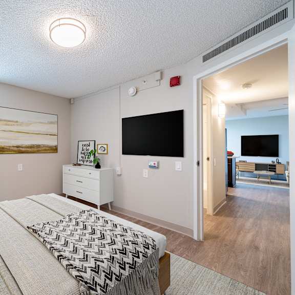 A living room with a grey couch, a wooden side table, and a rug.