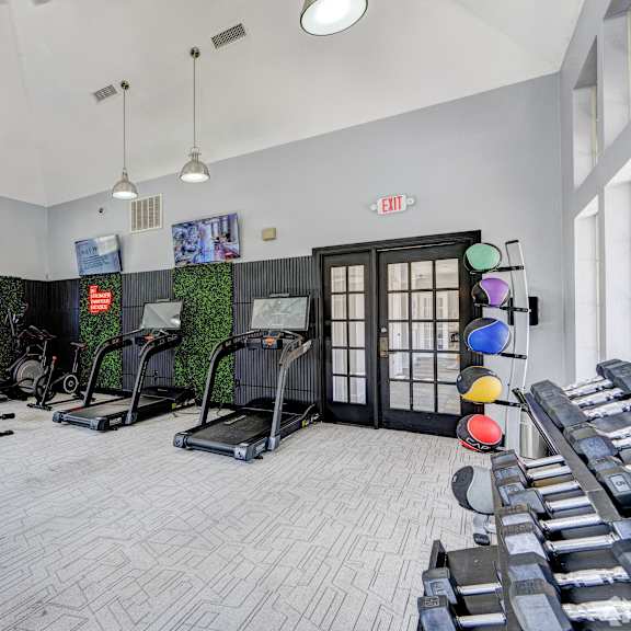 A gym with treadmills, weight benches and other equipment.at Villages of Briar Forest, Houston Texas