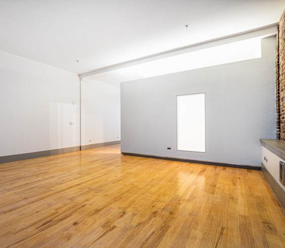 a living room with white walls and wooden floors and a window