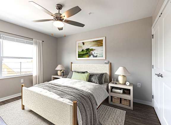 A bedroom with a bed, nightstands, and a ceiling fan.