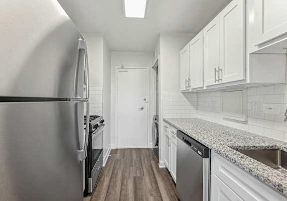 A kitchen with a stainless steel refrigerator and a granite countertop.