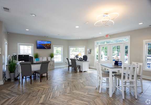 A spacious room with a dining table and chairs, a television, and a large window with a view of the outside.