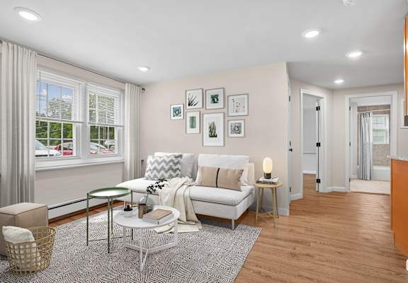 A living room with a white sofa, a glass table, and a grey rug.