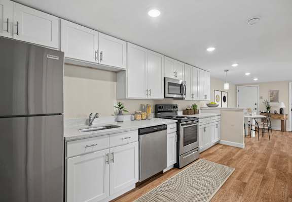 A modern kitchen with white cabinets and stainless steel appliances.