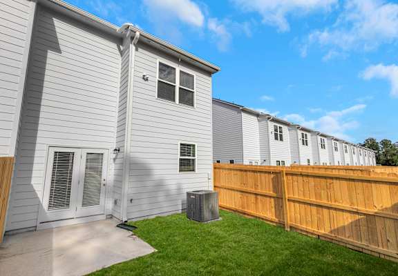 A grey house with a brown fence and a green lawn.