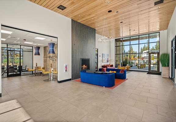 A spacious lobby with a blue couch and a fireplace.