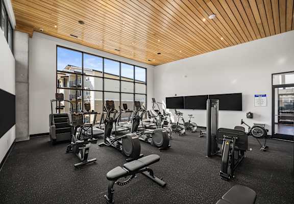 A gym with a variety of equipment including treadmills, weights, and exercise bikes.