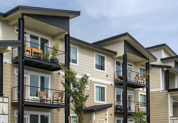 A row of townhouses with balconies and black railings.