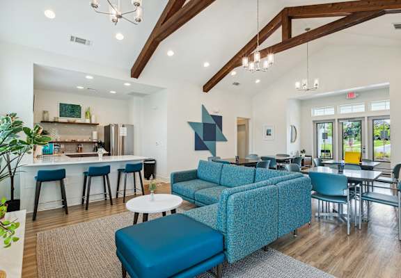 A modern living room with a blue sofa and a kitchen area in the background.