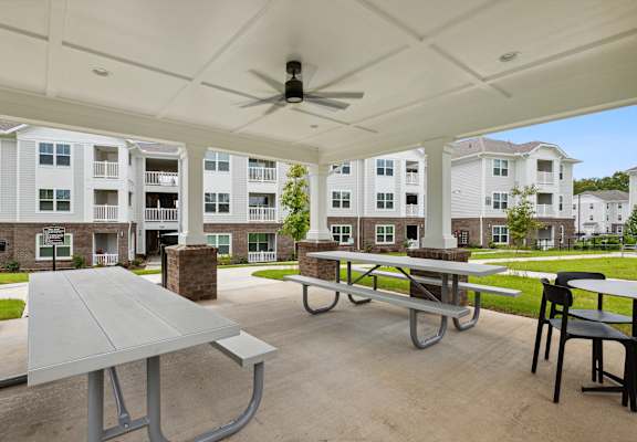 A patio with a table and chairs is set up in front of apartment buildings.