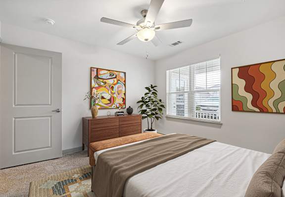 A bedroom with a bed, dresser, and a ceiling fan.