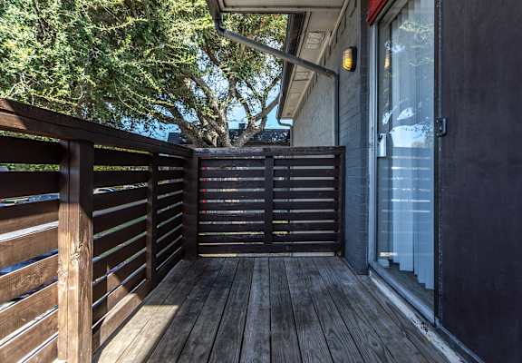 A wooden deck with a sliding glass door leading to a balcony.