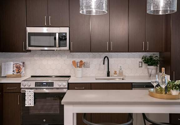 A modern kitchen with dark brown cabinets and a white countertop.