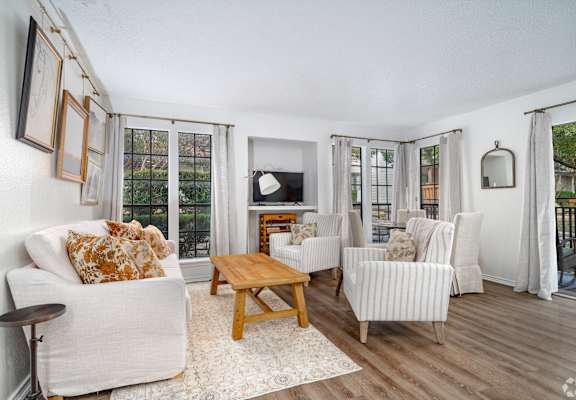 A living room with a white couch, a wooden coffee table, and a television.