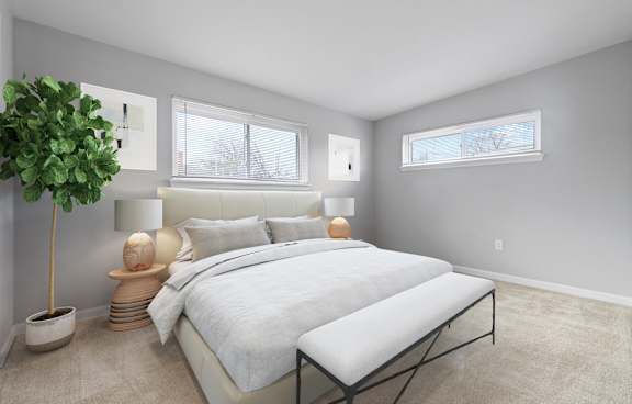 A bedroom with a large bed and a potted plant.