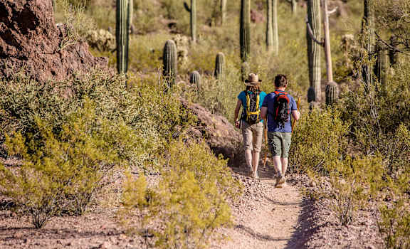 two people walking on a dirt trail in the desert at Links at High Resort, Rio Rancho