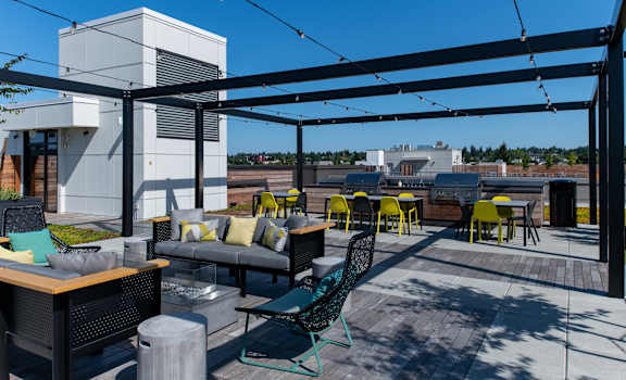 a roof top patio with chairs and tables and a building in the background