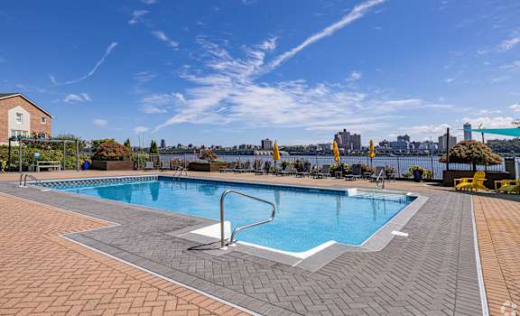 A large outdoor swimming pool with a tiled edge and a diving board.