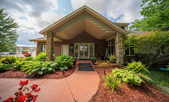 the front of a brick house with a walkway and plants