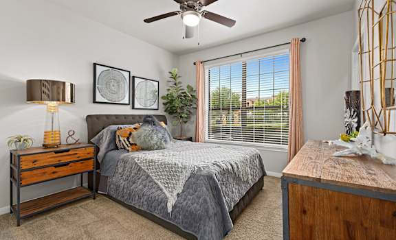 a bedroom with a large window and a ceiling fan