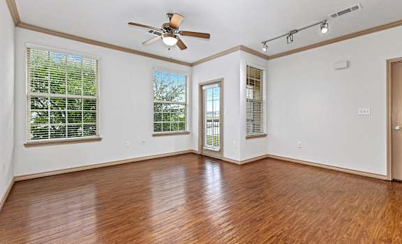 an empty living room with wood floors and a ceiling fan