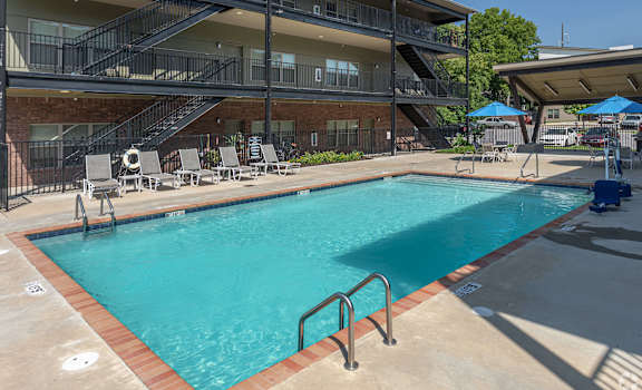 A swimming pool in front of a multi-story apartment building.
