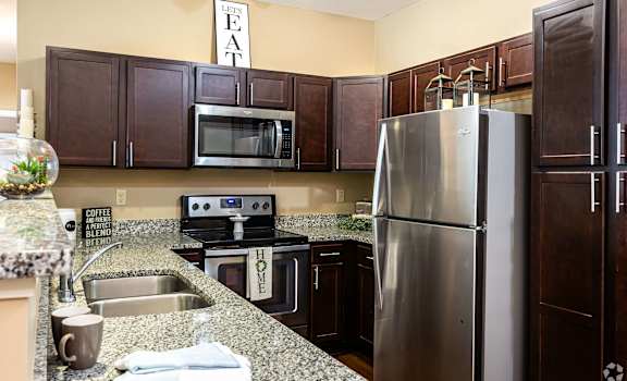 A kitchen with a refrigerator, sink, and cabinets.