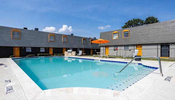 A large outdoor swimming pool with a sun lounger. at La Bella Apartments, Fort Worth