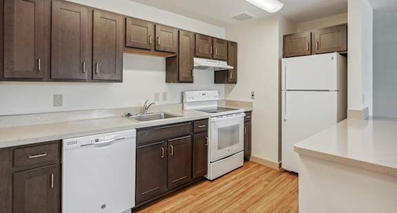 A kitchen with white appliances and brown cabinets.
