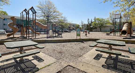 A playground with a slide, swings, and picnic tables.