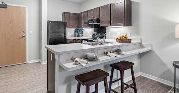a kitchen with a breakfast bar and stools next to a kitchen counter with a