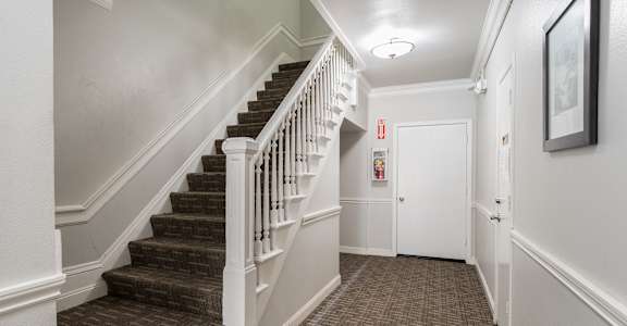 a hallway with stairs and a white door      and a door