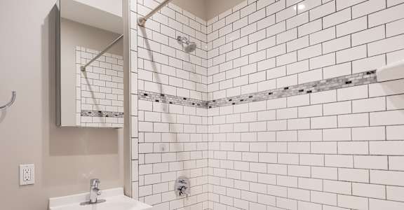a white bathroom with white tiles and a sink and a bath tub