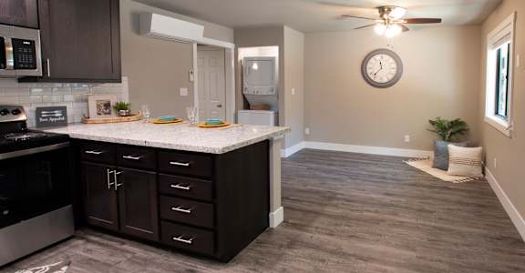 a kitchen and living room with a large clock on the wall