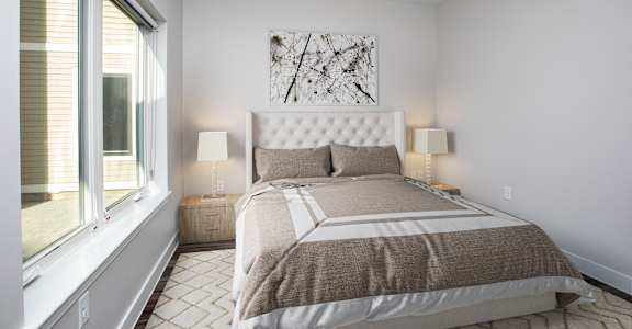 A bedroom with a large bed and a painting on the wall.