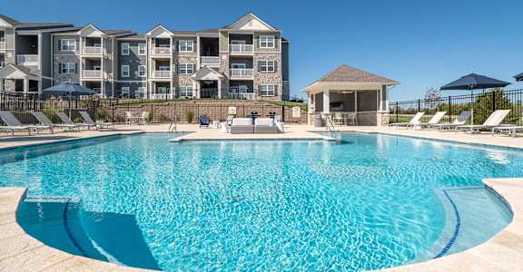 A large swimming pool in front of apartment buildings.
