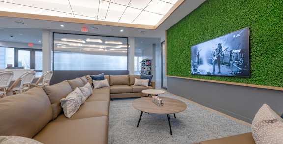 A modern living room with a green wall and a large screen TV. at Seacoast Residences Apartments, Oakland, ME, 03904